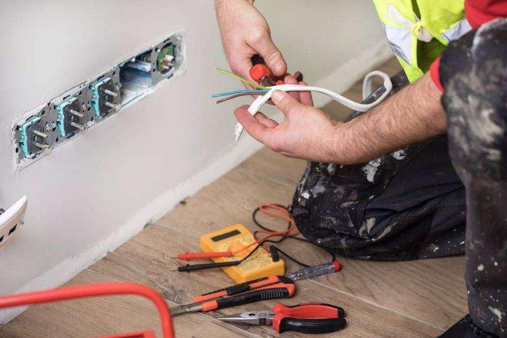 Electrician Wiring Sockets On A White Wall